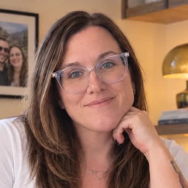 Tiffany Russell, smiling at her desk with her chin resting on her hand